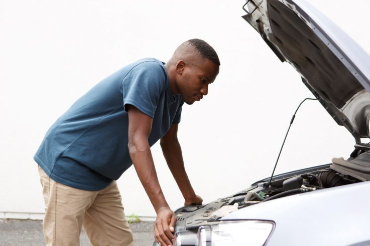 Man looking under the hood of car to find out why his Car Is Jerking Or Stuttering When Accelerating